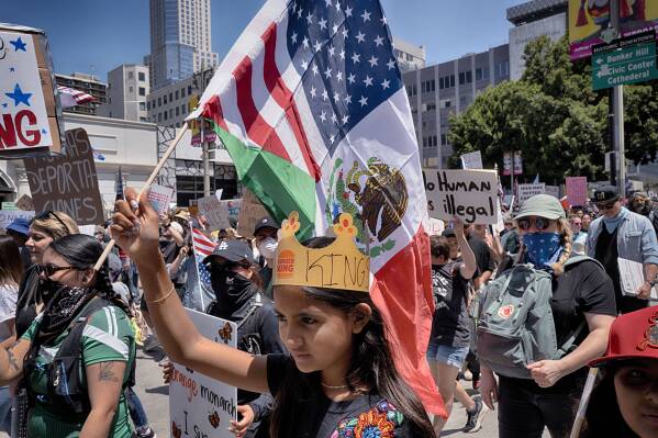 A young protester carries a combination Mexican and U.S. flag during a "No Kings" protest in downtown Los Angeles on Saturday, June 14, 2025. (AP Photo/Richard Vogel)