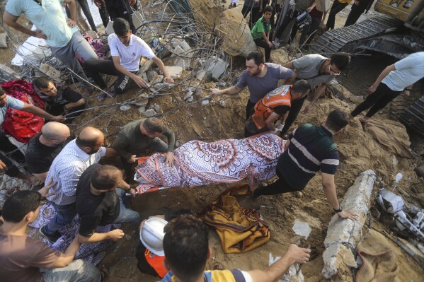 Palestinians carry a body of a dead person found under the rubble of a destroyed house after it was hit by an Israeli airstrike in town of Khan Younis, southern Gaza Strip, Tuesday, Oct. 24, 2023. (AP Photo/Mohammed Dahman)