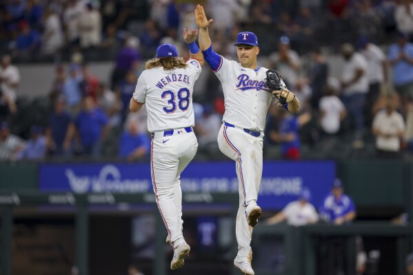 Texas Rangers' Davis Wendzel (38) and Nathaniel Lowe, right, celebrate after winning a baseball game against the Seattle Mariners, Wednesday, April 24, 2024, in Arlington, Texas. (AP Photo/Gareth Patterson)