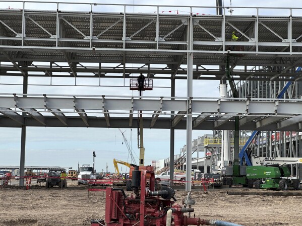 A worker stands on a mechanical lift amid the construction of Hyundai's first U.S. plant for manufacturing electric vehicles on Wednesday, Oct. 25, 2023, in Ellabell, Ga. Hyundai and battery-making partner LG Energy Solution are investing $7.6 million in the sprawling plant site west of Savannah, Georgia, where the companies plan to make 300,000 electric vehicles and the batteries that power them each year. (AP Photo/Russ Bynum)