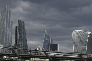 A man walks across the Millennium Bridge in London, Wednesday, May 13, 2020, as the country continues in lockdown to help stop the spread of coronavirus. Despite the relaxation of some of the coronavirus lockdown measures on Wednesday central London was still quite. (AP Photo/Tony Hicks)
