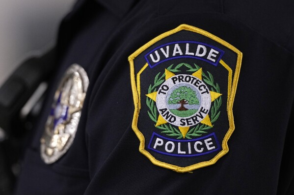 A Uvalde police officers patch a badge are seen as he stands watch over a special city council meeting in Uvalde, Texas, Thursday, March 7, 2024. Almost two years after the deadly school shooting in Uvalde that left 19 children and two teachers dead, the city council met to discuss the results of an independent investigation it requested into the response by local police officers. (AP Photo/Eric Gay)