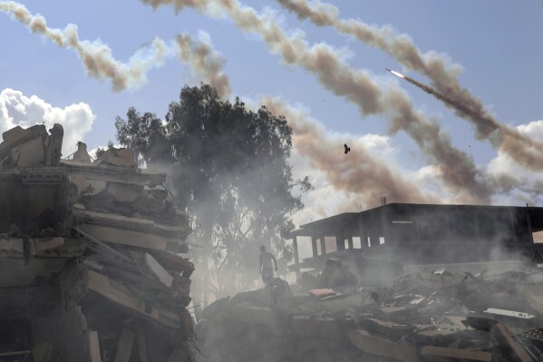 Rockets are fired from the Gaza Strip toward Israel over destroyed buildings following Israeli airstrikes on Gaza City, central Gaza Strip, Thursday, Oct. 19, 2023. (AP Photo/Mohammed Dahman)