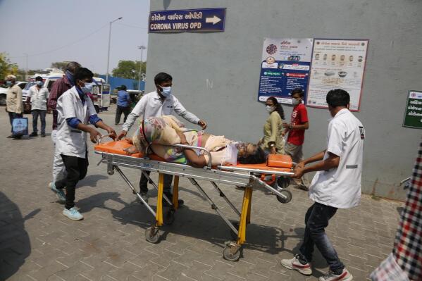 Health workers bring a patient to be admitted at a government COVID-19 hospital in Ahmedabad, India, Tuesday, April 27, 2021. Coronavirus cases in India are surging faster than anywhere else in the world. (AP Photo/Ajit Solanki)