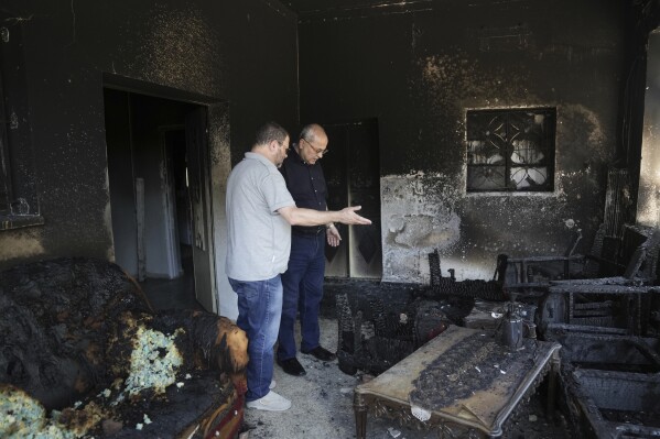 Israeli lawmakers Ofer Cassif, left, and Ahmad Tibi inspect a torched home, days after it was set on fire by Jewish settlers, in the West Bank town of Turmus Ayya, Saturday, June 24, 2023. Israeli settlers entered the town, setting fire to Palestinian cars and homes after four Israelis were killed by Palestinian gunmen in the northern West Bank on Tuesday. (AP Photo/Mahmoud Illean)