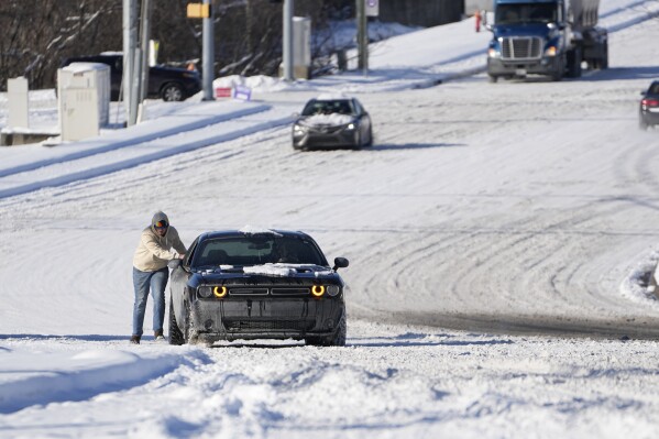 A motorist is pushed through the snow Tuesday, Jan. 16, 2024, in Nashville, Tenn. A snowstorm blanketed the area with up to eight inches of snow and frigid temperatures.(AP Photo/George Walker IV)