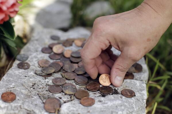 FILE - In this Aug. 6, 2019, photo, Janie Clark places pennies at a memorial her husband, Ansol Clark, constructed near the Kingston Fossil Plant in Kingston, Tenn. Clark arrived to work at the Tennessee Valley Authority's Kingston Fossil Plant just hours after the Dec. 22, 2008, spill. He labored long hours in the coal ash sludge with few or no days off for months at a time until he was too sick to work in 2013. He died in 2021 from a rare blood cancer that he believed was caused by exposure to the ash. (AP Photo/Mark Humphrey, File)