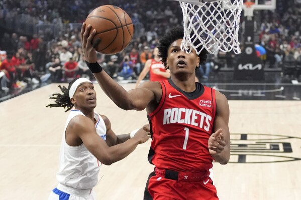 Houston Rockets forward Amen Thompson, right, shoots as Los Angeles Clippers guard Terance Mann defends during the first half of an NBA basketball game Sunday, April 14, 2024, in Los Angeles. (AP Photo/Mark J. Terrill)