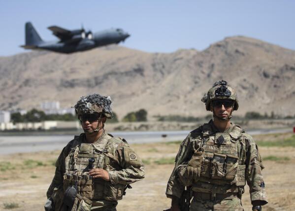 In this image provided by the Department of Defense, two paratroopers assigned to the 1st Brigade Combat Team, 82nd Airborne Division conduct security while a C-130 Hercules takes off during a evacuation operation in Kabul, Afghanistan, Wednesday, Aug. 25, 2021. (Department of Defense via AP)
