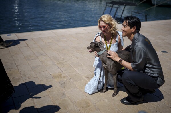 A fan, left, poses for a photo with Eddie Peng and his dog Xin during an interview for the film 'Black Dog' at the 77th international film festival, Cannes, southern France, Tuesday, May 21, 2024. (Photo by Andreea Alexandru/Invision/AP)