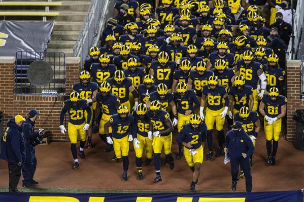FILE - Michigan head coach Jim Harbaugh, bottom right, leads his team out of the Michigan Stadium tunnel before an NCAA college football game against Wisconsin in Ann Arbor, Mich., Nov. 14, 2020. Michigan Stadium's tunnel will be a little wider next season. The school confirmed Monday, Jan. 23, 2023, that it will remove a portable section of seats from the front of the tunnel to give players, coaches and staff members more room to enter and exit the football field. (AP Photo/Tony Ding, File)