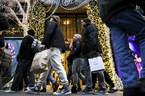 FILE - Shoppers carry shopping bags down Fifth Avenue, Monday, Dec. 19, 2022, in New York. The National Retail Federation, the nation’s largest retail trade group, expects holiday sales growth will ease to a range of 3% to 4%, compared with 5.4% growth a year ago. The forecast, released Thursday, Nov. 2, 2023, comes as shoppers keep spending, powered by sturdy hiring, low unemployment and healthy household finances. (AP Photo/Julia Nikhinson, File)