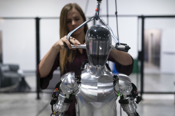 FILE - AI engineer Jenna Reher works on humanoid robot Figure 01 at Figure AI's test facility in Sunnyvale, Calif., Oct. 3, 2023. ChatGPT-maker OpenAI is looking to fuse its artificial intelligence systems into the bodies of humanoid robots as part of a new deal with robotics startup Figure. Sunnyvale, California-based Figure announced the partnership Thursday, Feb. 29, 2024, along with $675 million in venture capital funding from a group that includes Amazon founder Jeff Bezos as well as Microsoft, chipmaker Nvidia and the startup-funding divisions of Amazon, Intel and OpenAI. (AP Photo/Jae C. Hong, File)