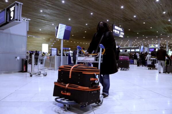Gaye Camara wheels her bags through Terminal 2E of Paris' Charles de Gaulle airport to catch a New York flight Monday, Nov. 8, 2021, to be re-united with her husband Mamadou. The couple from Senegal haven't seen each other since Jan. 2020, before the United States closed its borders to foreign visitors. She lives in France. He lives in New York. More than a year and a half after COVID-19 concerns prompted the U.S. to close its borders to international travelers from countries including Brazil, China, India, South Africa, the United Kingdom and much of Europe, restrictions are shifting to focus on vaccine status. (AP Photo/John Leicester).