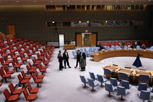 People stand in the mostly empty Security Council chambers at United Nations headquarters, Thursday, Dec. 21, 2023. The United States, key allies and Arab nations are engaging in high-level diplomacy in hopes of avoiding another U.S. veto of a new U.N. resolution on desperately needed aid to Gaza ahead of a long-delayed vote. (AP Photo/Seth Wenig)