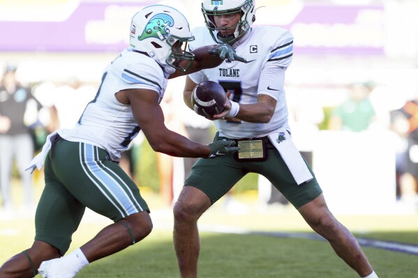 Tulane's Michael Pratt (7) hands the ball off to Makhi Hughes, left, during an NCAA college football game against East Carolina on Saturday, Nov. 4, 2023, in Greenville N.C. (Scott Davis/News & Record via AP)