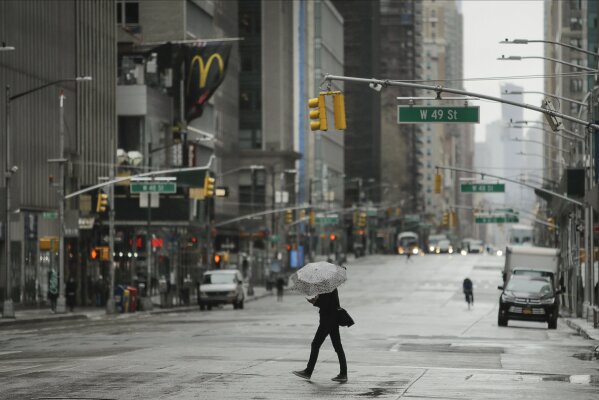 A pedestrians crosses a mostly empty Sixth Avenue during the coronavirus outbreak, Friday, April 3, 2020, in New York. The new coronavirus causes mild or moderate symptoms for most people, but for some, especially older adults and people with existing health problems, it can cause more severe illness or death. (AP Photo/Frank Franklin II)