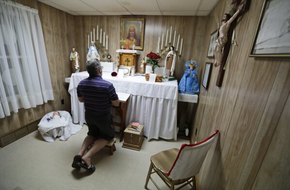 In this Aug. 9, 2019, photo Ron Sattler kneels and prays in front of the altar in Canton, Ohio. Late in the summer of 1939, crowds of strangers started showing up at Rhoda Wise’s house next to a city dump in Ohio after she let it be known that miracles were occurring in her room. Eight decades later, people still make pilgrimages to the wood frame bungalow at the edge of Canton, seeking their own miracles. (AP Photo/Tony Dejak)