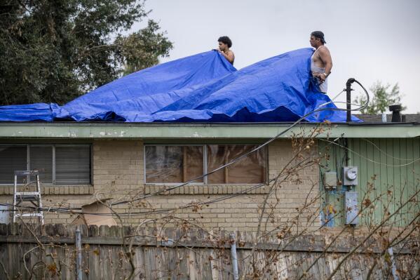 Men cover a roof with tarps, Monday, Sept. 6, 2021, a week after Hurricane Ida swept through the area. (Chris Granger/The Times-Picayune/The New Orleans Advocate via AP)