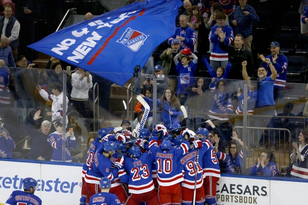 The New York Rangers and their fans celebrate their shootout victory over the New York Islanders in an NHL hockey game Saturday, April 13, 2024, in New York. The Rangers rallied to defeat the Islanders for a franchise-record 54th win. (AP Photo/John Munson)