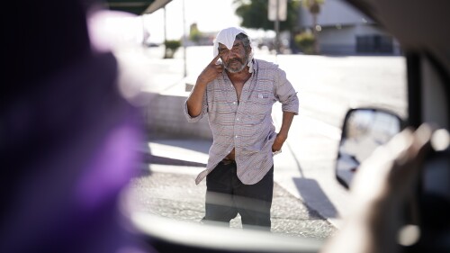 A man, who is homeless, talks to Maribel Padilla, left, of the Brown Bag Coalition, after receiving a cold, wet towel, Thursday, July 20, 2023, in Calexico, Calif. Once temperatures hit 113 degrees Fahrenheit (45 Celsius), Padilla and the Brown Bag Coalition meet up with people who are homeless in Calexico, providing them with cold, wet towels, and some refreshments to help them endure the scorching temperatures. (AP Photo/Gregory Bull)