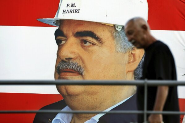A man passes a poster of slain Lebanese Prime Minister Rafik Hariri in Beirut, Lebanon, Tuesday, Aug. 18, 2020. A U.N.-backed tribunal on Tuesday convicted one member of the Hezbollah militant group and acquitted three others of involvement in the 2005 assassination of former Lebanese Prime Minister Rafik Hariri. (AP Photo/Bilal Hussein)