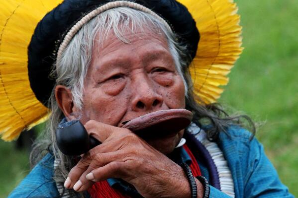 FILE - In this Aug. 26, 2019 file photo, Kayapo tribal leader Raoni Metuktire smokes a pipe after a press conference in Bidart, southwestern France. The Indigenous leader emblematic of the fight for the preservation of the Amazon forest in Brazil was hospitalized with symptoms of pneumonia and tested positive for the new coronavirus, according to the Raoni Institute on Monday, Aug. 31, 2020. (AP Photo/Bob Edme, File)