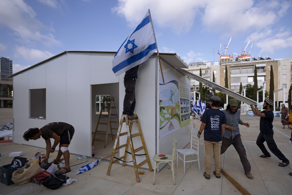 Right wing Israeli activists from the Nachala Settlement Movement erect a temporary structure as part of a protest calling for the establishment of new Jewish settlements in the occupied West Bank, at Habima Square in Tel Aviv, July 12, 2022. The Israeli Supreme Court on Wednesday July 27, 2022, has cleared the way for residents of the Jewish West Bank settlement outpost of Mitzpe Kramim to remain in their homes, overturning an earlier eviction order that determined the land had been bought illegally. Palestinians fear this could set a precedent for future disputes over Jewish settlements being built on privately owned Palestinian land. (AP Photo/Oded Balilty)