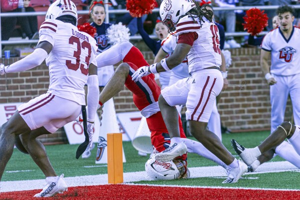 Liberty's Kaidon Salter, center, is upended short of the goal line against Massachusetts' Darius Gooden, Derrieon, Craig and Jerrod Cameron during the second half of an NCAA college football game, Saturday, Nov. 18, 2023, in Lynchburg, Va. (AP Photo/Robert Simmons)