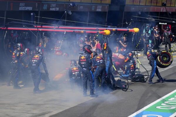 Red Bull mechanics work to extinguish a fire in Max Verstappen of the Netherlands car during the Australian Formula One Grand Prix at Albert Park, in Melbourne, Australia, Sunday, March 24, 2024. (AP Photo/Scott Barbour,Pool)