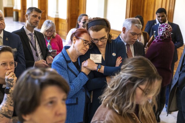 FILE - Jennifer Bowie, center left, and Aaron Baker, center right, become emotional while watching discussion of SB 140 on a video monitor in the Capitol before it gets final approval at the state Senate in Atlanta, Tuesday, March 21, 2023. A federal judge on Tuesday, Sept. 5, allowed Georgia to resume enforcing a ban on hormone replacement therapy for transgender people under 18. Judge Sarah Geraghty put her previous order blocking the ban on hold after a federal appeals court allowed Alabama to enforce a similar restriction. (Arvin Temkar/Atlanta Journal-Constitution via AP, File)