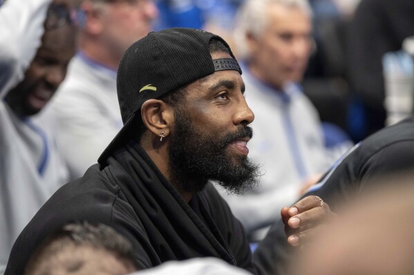 Dallas Mavericks' Kyrie Irving watches from the bench during the first half of an NBA basketball game against the Detroit Pistons, Friday, April 12, 2024, in Dallas. Irving did not play due to hamstring soreness. (AP Photo/Jeffrey McWhorter)