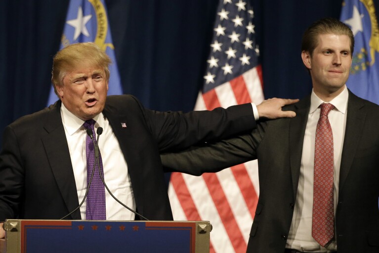 FILE - Republican presidential candidate Donald Trump, left, puts his hand on the shoulder of his son, Eric, while speaking at a caucus night rally, Feb. 23, 2016, in Las Vegas. A New York judge ruled Friday, Feb. 16, 2024, against Trump, imposing a $364 million penalty over what the judge ruled was a yearslong scheme to dupe banks and others with financial statements that inflated the former president's wealth. (AP Photo/Jae C. Hong, File)