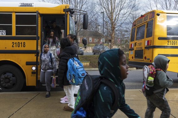 Rock Creek Forest Elementary School students exit a diesel bus before attending school, Friday, Feb. 2, 2024, in Chevy Chase, Md. At right is an electric school bus. (AP Photo/Tom Brenner)