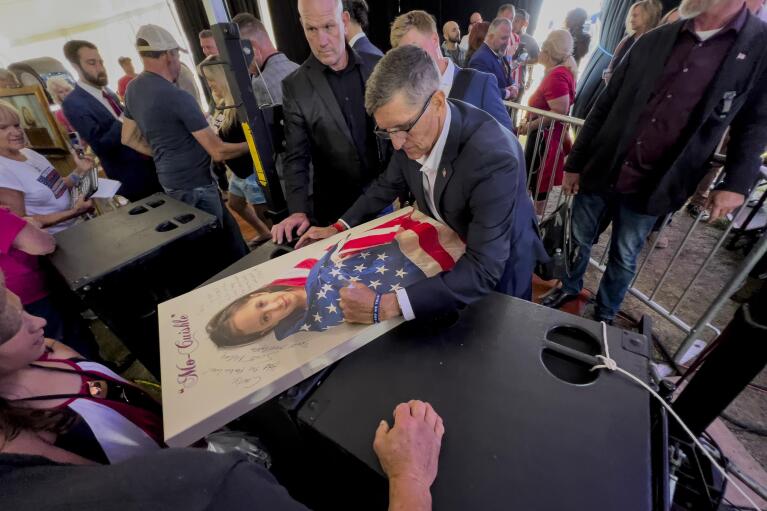 Michael Flynn, a retired three-star general who served as President Donald Trump’s national security advisor, autographs a picture of a girl wrapped in an American flag during the ReAwaken America Tour at Cornerstone Church in Batavia, N.Y., Friday, Aug. 12, 2022. Flynn, one of the tour’s founders and its star, warned the crowd that they were in the midst of a “spiritual war” and urges people to get involved in local politics." (AP Photo/Carolyn Kaster)