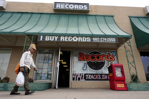 A pedestrian walks past the entrance to Tracks In Wax record shop, Thursday, April 18, 2024, in Phoenix. Special LP releases, live performances and at least one giant block party are scheduled around the U.S. Saturday as hundreds of shops celebrate Record Store Day amid a surge of interest in vinyl and the day after the release of Taylor Swift's latest album. (AP Photo/Ross D. Franklin)