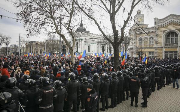 Riot police officers stand in line in front of protesters during a protest initiated by the Movement for the People and members of Moldova's Russia-friendly Shor Party, against the pro-Western government and low living standards, in Chisinau, Moldova, Tuesday, Feb. 28, 2023. Thousands of protesters returned to Moldova's capital Tuesday to demand that the country'snew pro-Western governmentfully subsidize citizens' winter energy bills amid skyrocketing inflation. (AP Photo/Aurel Obreja)