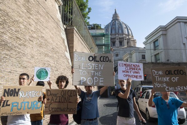 Activists hold up signs outside the Vatican as Pope Francis meets with oil executives, Friday, June 14, 2019. The meeting marked the second year that Francis has invited oil and financial sector executives to the Vatican to impress upon them his concern that preserving God’s creation is one of the fundamental challenges facing humankind today. Signs in Italian read "Don't steal our future", left, and "Climate emergency is not an opinion!", second from right.  (Claudio Peri/ANSA via AP)