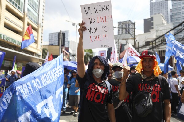 A man holds a poster during an International Labor Day protest near the Presidential Palace in Manila, Philippines on Wednesday, May 1, 2024. Hundreds of Filipino workers from various labor groups took to the streets to celebrate Labor Day and demand higher wages and job security amid rising food and oil prices.  (AP Photo/Basilio Sepe)