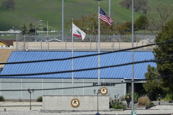 FILE - An official walks toward an entrance to the Federal Correctional Institution in Dublin, Calif., March 11, 2024. A judge on Friday, March 15, appointed a special master to oversee the federal prison — dubbed the "rape club" by prisoners and workers alike — in the San Francisco Bay Area. The judge's order encompasses the prison in Dublin, located about 21 miles (34 kilometers) east of Oakland. (AP Photo/Jeff Chiu, File)