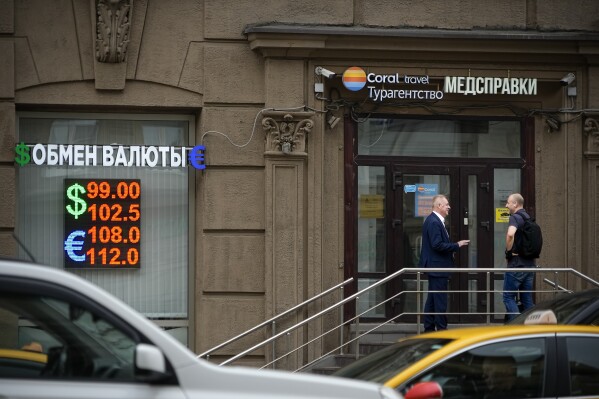Two men talk to each other at the entrance of a currency exchange office in Moscow, Russia, Monday, Aug. 14, 2023. Russia’s central bank made a big interest rate hike of 3.5 percentage points on Tuesday, Aug. 15, 2023, an emergency move designed to fight inflation and strengthen the ruble after the country's currency reached its lowest value since early in the war with Ukraine. (AP Photo/Alexander Zemlianichenko)