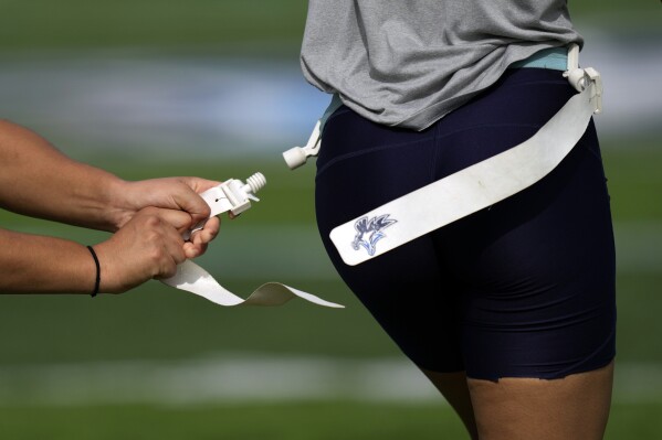 A defender pulls a teammate's flag during a drill at a training session for Keiser University's flag football team in West Palm Beach, Fla., Thursday, Nov. 30, 2023. The no-contact sport featuring plenty of offensive action has really been on the rise for a while, with girls-specific teams and leagues springing up from coast to coast. (AP Photo/Rebecca Blackwell)