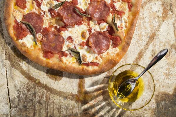 This image released by Milk Street shows a recipe for pizza with salami and smoked mozzarella. (Milk Street via AP)