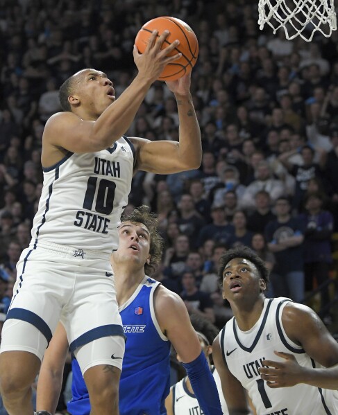 El guardia del estado de Utah, Darius Brown II (10), dispara mientras el delantero del estado de Boise, Tyson Degenhart, defiende durante la segunda mitad de un partido de baloncesto universitario de la NCAA el sábado 10 de febrero de 2024 en Logan, Utah.  (Eli Lucero/The Herald Journal vía AP)