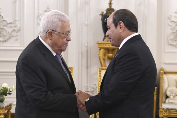 In this photo provided by Egypt's presidency media office, Egyptian President Abdel Fattah el-Sissi, right, greets Palestinian President Mahmoud Abbas, during the International peace summit pose for a group picture at the New Administrative Capital, just outside Cairo, Egypt, Saturday, Oct. 21, 2023. (Egyptian Presidency Media Office via AP)