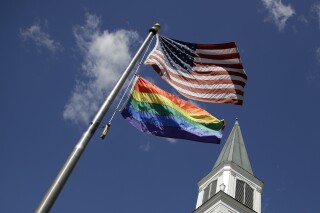 FILE - A gay Pride rainbow flag flies with the U.S. flag in front of the Asbury United Methodist Church in Prairie Village, Kan., on Friday, April 19, 2019. As of June 2023, more than 6,000 United Methodist congregations — a fifth of the U.S. total — have now received permission to leave the denomination amid a schism over theology and the role of LGBTQ people in the nation's second-largest Protestant denomination. (AP Photo/Charlie Riedel, File)