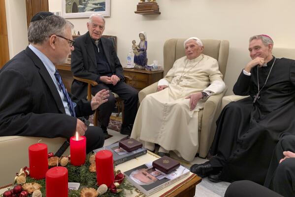 Pope Emeritus Benedict XVI, third from left, meets with the winners of the 2022 Ratzinger Prize, Joseph Halevi Horowitz Weiler, left, and father Michel Fedou, partially hidden at right, at the Mater Ecclesiae monastery inside the Vatican where Benedict XVI lives, in this photo taken Thursday, Dec. 1, 2022. Second from left, is the foundation's president Father Federico Lombardi, and fourth from left is Benedict XVI's long-time personal secretary Bishop Georg Gänswein. (Fondazione Vaticana J.Ratzinger via AP)
