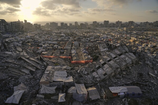 A tent camp for displaced Palestinians stretches among the ruins of buildings destroyed by Israeli bombardments in west of Gaza City, Saturday, June 21, 2025. (AP Photo/Jehad Alshrafi)
