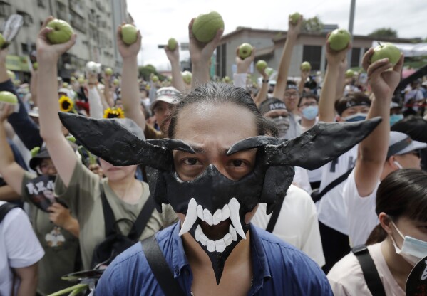 A supporter of opposition Taiwan People's Party (TPP) wears a devil mask as other supporters hold guavas, symbolizing dishonored ballots, during a march to protest against Lai Ching-te's ruling Democratic Progressive party, a day before his presidential inauguration in Taipei, Taiwan, Sunday, May 19, 2024.(AP Photo/Chiang Ying-ying)
