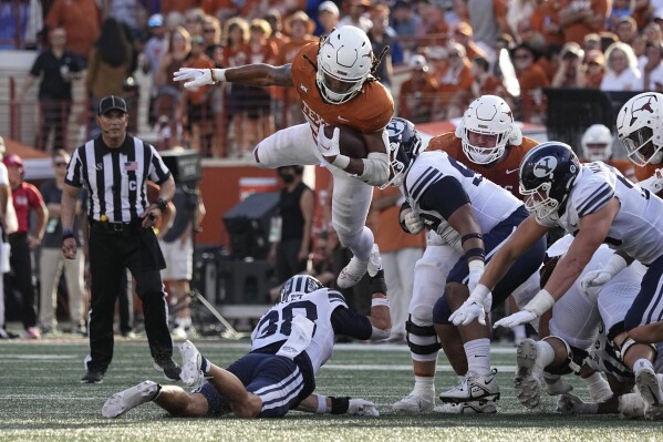 Texas running back Jonathon Brooks (24) is upended by BYU safety Crew Wakley (38) on a run during the second half of an NCAA college football game in Austin, Texas, Saturday, Oct. 28, 2023. (AP Photo/Eric Gay)